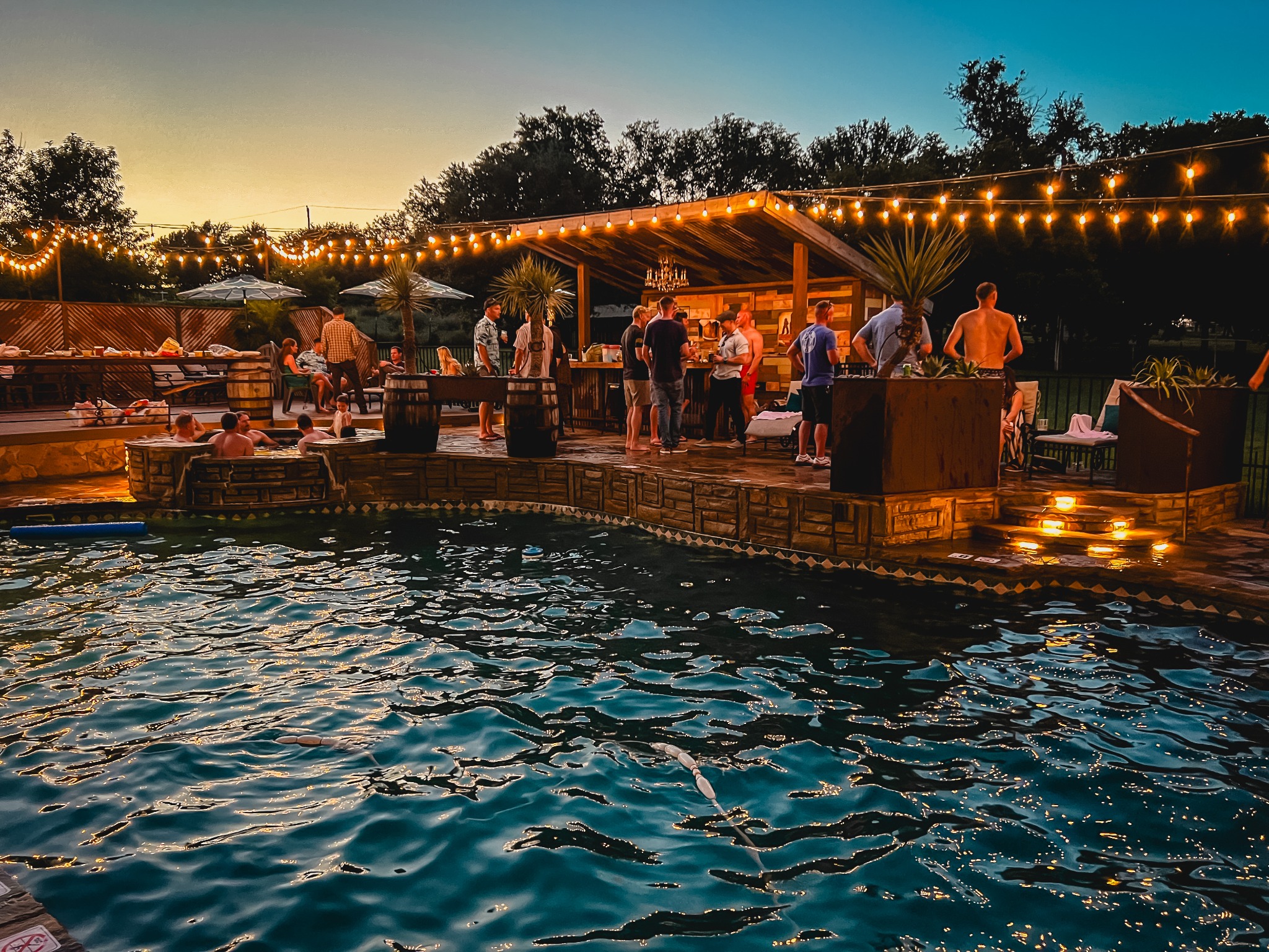 Friends gathered beside the pool at Cowtown Casa after sunset